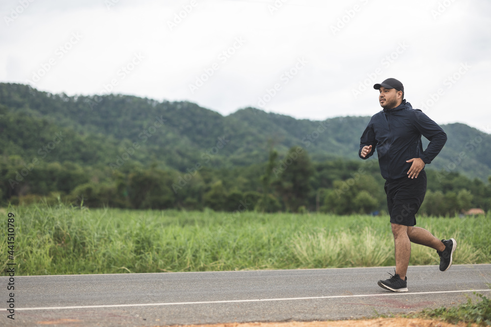 Asia man wearing sportswear running on the road with mountain background. Young man jogging for exercise in the nature. healthy lifestyle and sports concept Asia man wearing sportswear running on the road with mountain background. Young man jogging for exercise in the nature. healthy lifestyle and sports concept