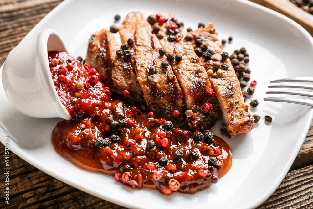 Plate with tasty roasted meat and peppercorn sauce on wooden background, closeup Plate with tasty roasted meat and peppercorn sauce on wooden background, closeup