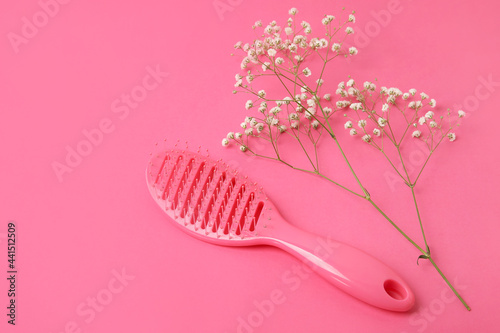 Hair brush and flowers on color background