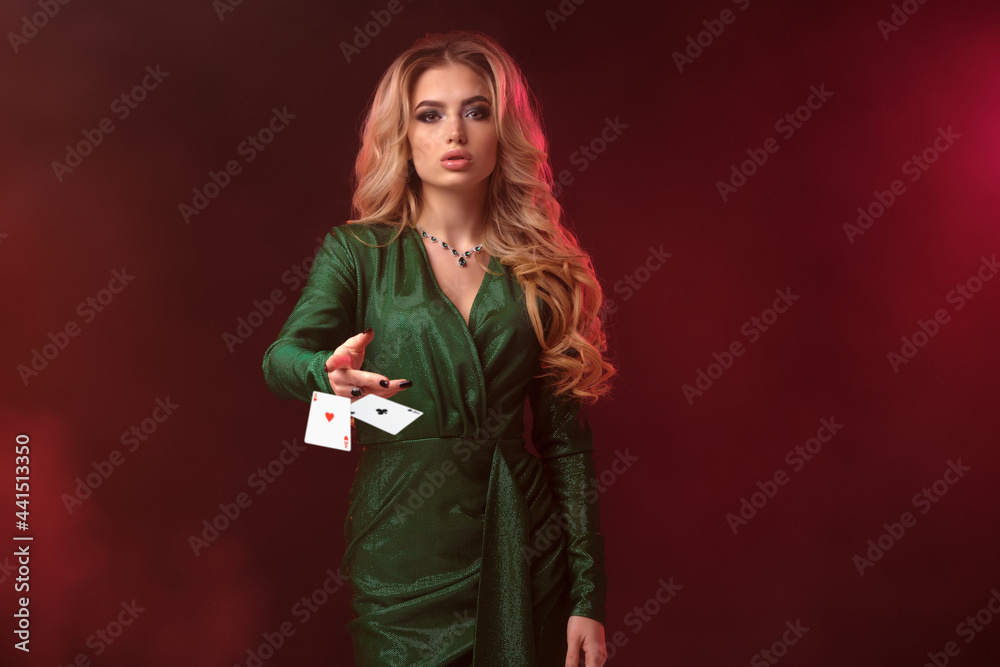Blonde model, bright make-up, in green dress and jewelry. Holding something, throwing it, posing on colorful smoky background. Copy space, close up Blonde model, bright make-up, in green dress and jewelry. Holding something, throwing it, posing on colorful smoky background. Copy space, close up