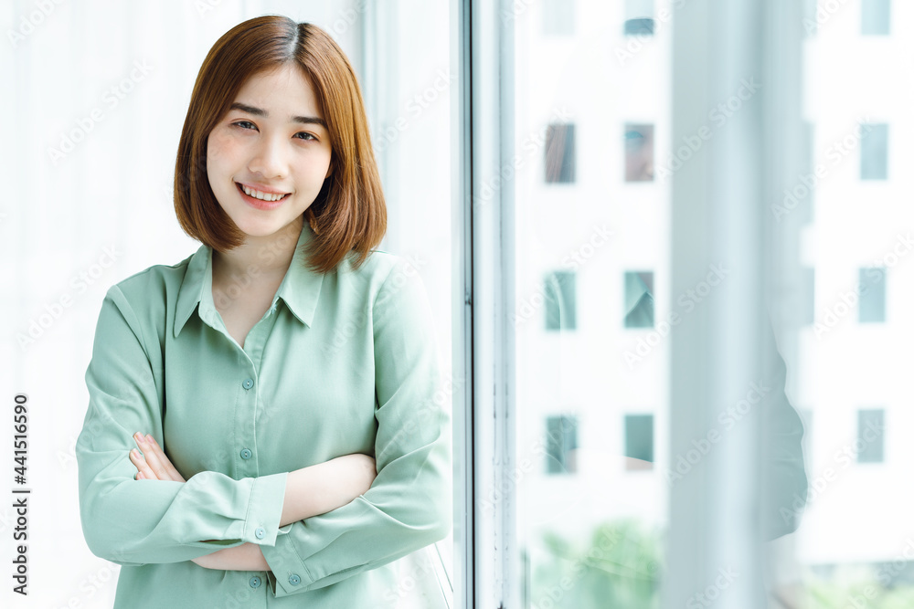 Portrait of young businesswoman standing by the company window Portrait of young businesswoman standing by the company window