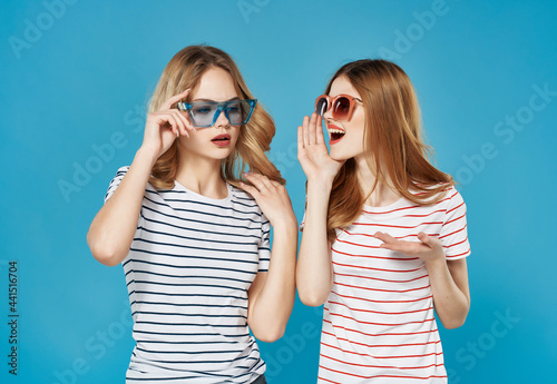 two cute girlfriends summer fashion fun hug blue background