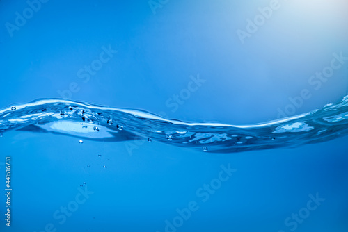 Water waves with air bubbles in clear blue water.