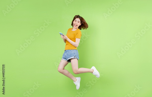 Young Asian girl jumping on a green background