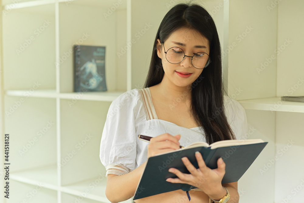 Half-length portrait of female with eyeglasses reading book in workspace Half-length portrait of female with eyeglasses reading book in workspace