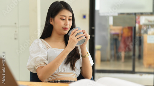 Portrait of female college student drinking coffee while reading book