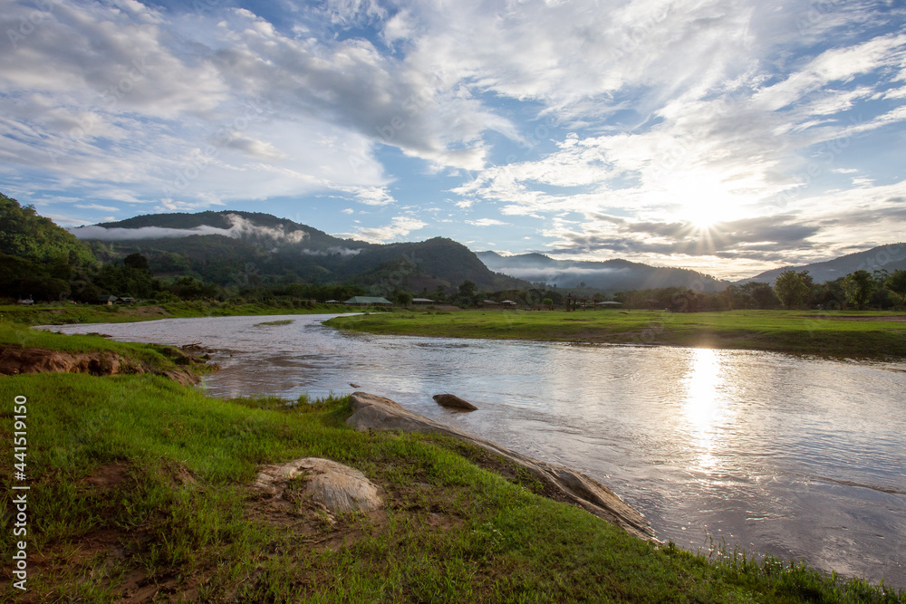 Mountain landscape, sunset, fog, clouds after the rain on the mountain, clear sky, river, light green grass Gives a cool and refreshing feeling in the background