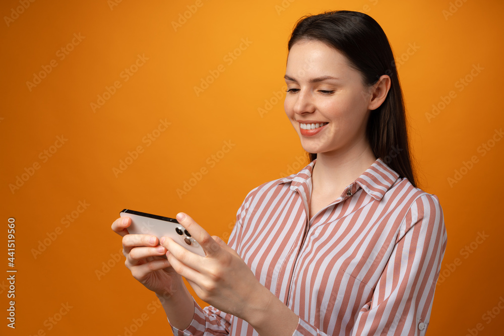 Portrait of young attractive woman using her smartphone against yellow background Portrait of young attractive woman using her smartphone against yellow background