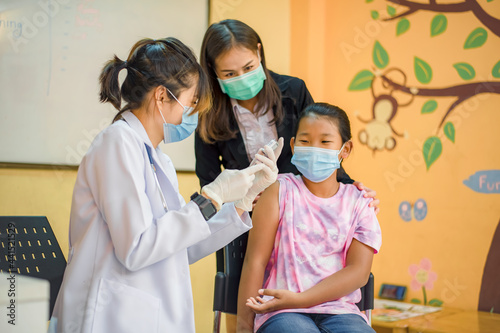 Coronavirus vaccination. Covid-19 vaccine. Doctor giving vaccinations to schoolchildren at School to prevent a serious epidemic among schoolchildren. Little boy getting flu shot. Virus prevention.