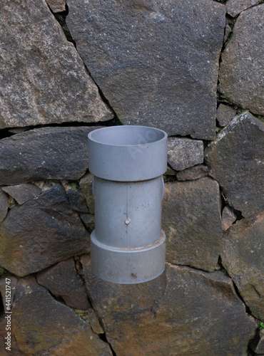 sewer pipe close-up with the stone embankment in the background