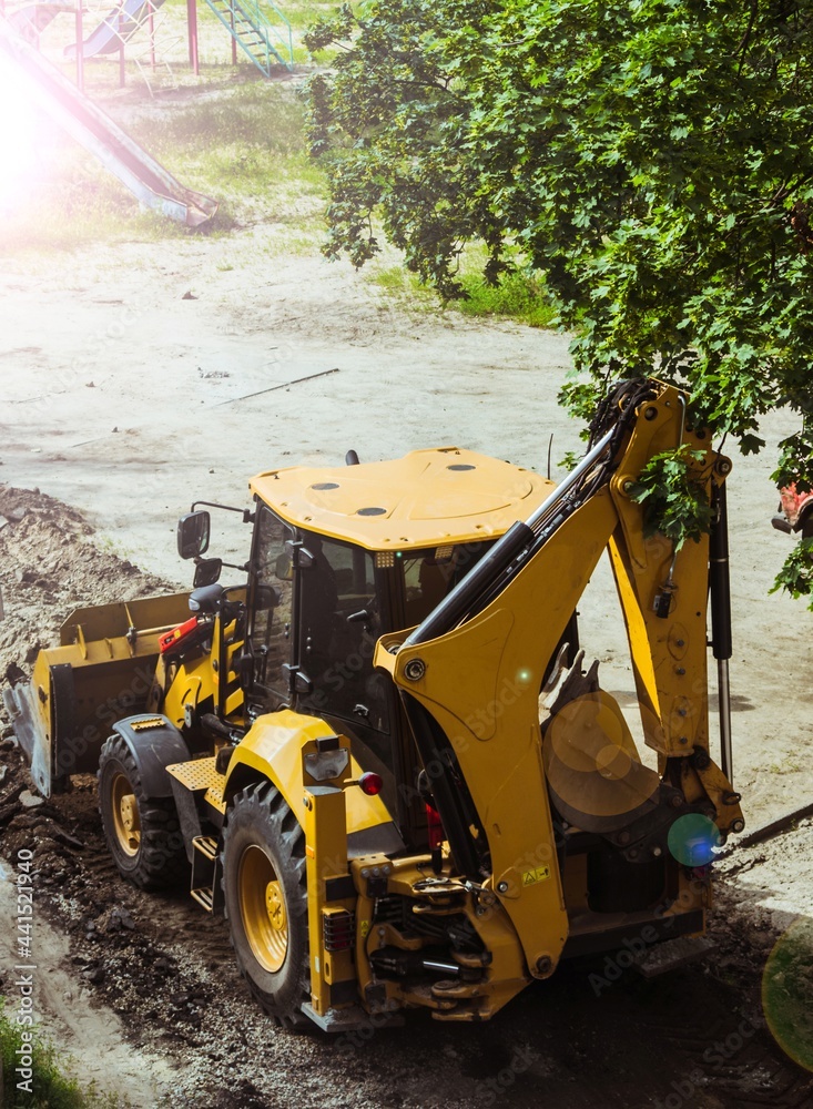 Yellow excavator loader removes the remains of broken asphalt. Yellow excavator loader removes the remains of broken asphalt.