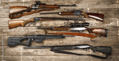 Photos Many hunting rifles on weathered wooden surface
