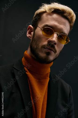 stylish man with glasses orange sweater coat black background 