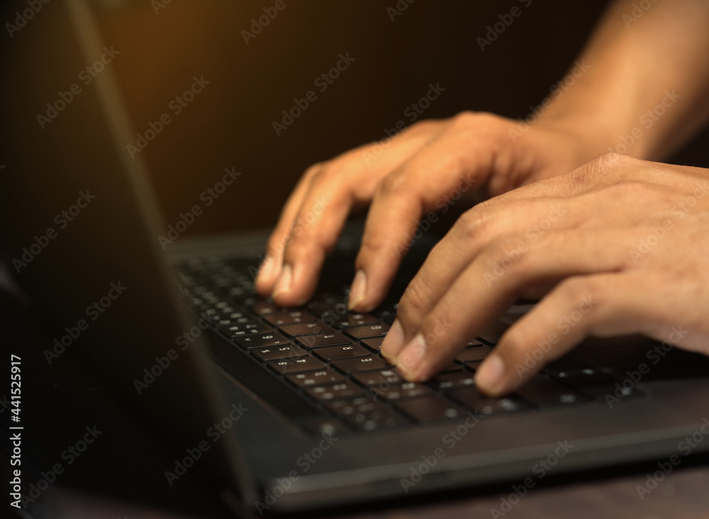 Hands of a business man working from home using a notebook computer, indoors, with flare and focus selected. Hands of a business man working from home using a notebook computer, indoors, with flare and focus selected.