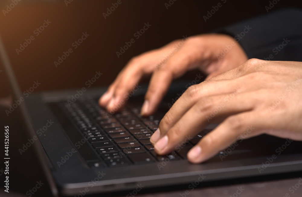 Hands of a business man working from home using a notebook computer, indoors, with flare and focus selected. Hands of a business man working from home using a notebook computer, indoors, with flare and focus selected.