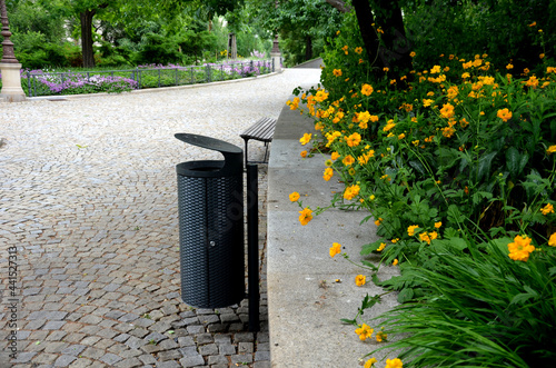 bench at a retaining wall in a park of black bushes early spring perennials on a high flowerbed path of granite cubes
 photo