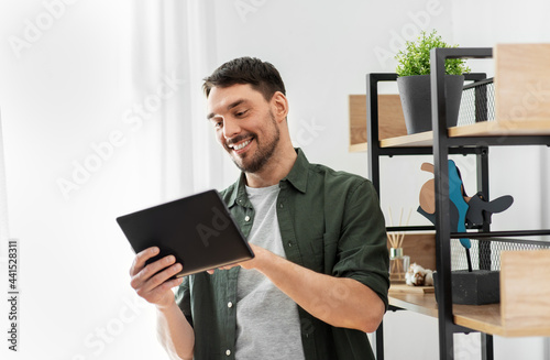 home improvement and decoration and people concept - happy smiling man with tablet pc computer standing at shelf at home
