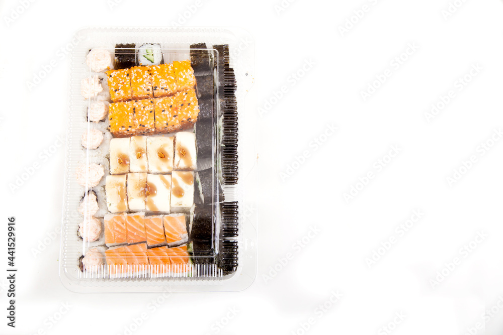 Plastic box with a set of various sushi, rolls on a white background. Home delivery of groceries. Copy spaes. Plastic box with a set of various sushi, rolls on a white background. Home delivery of groceries. Copy spaes.