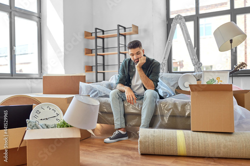 moving, eviction and real estate concept - sad man with boxes at new home photo