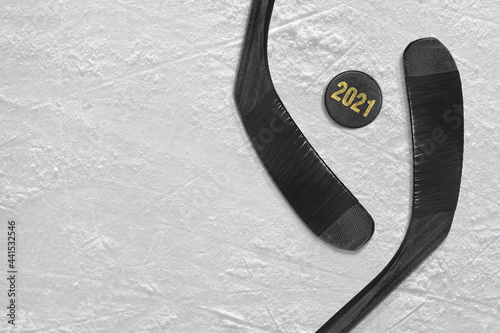 Two sticks, a puck and a fragment of a hockey rink