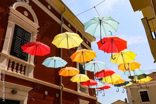 Fröhliche Regenschirme im Sonnenlicht als Himmel einer Gasse am Mittelmeer