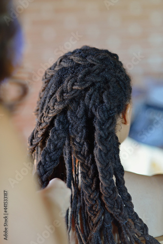 Woman of African ethnicity combing her hair with braids