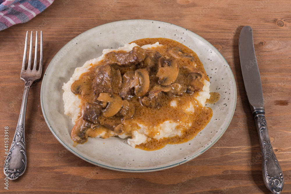 Homemade beef stroganoff with beef and mushrooms with mashed potatoes - lunch portion on a plate, close-up Homemade beef stroganoff with beef and mushrooms with mashed potatoes - lunch portion on a plate, close-up