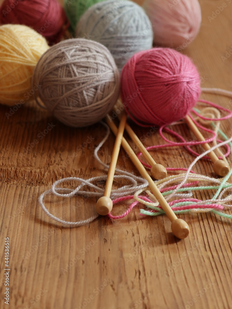 Colorful balls of wool and knitting needles on wooden background