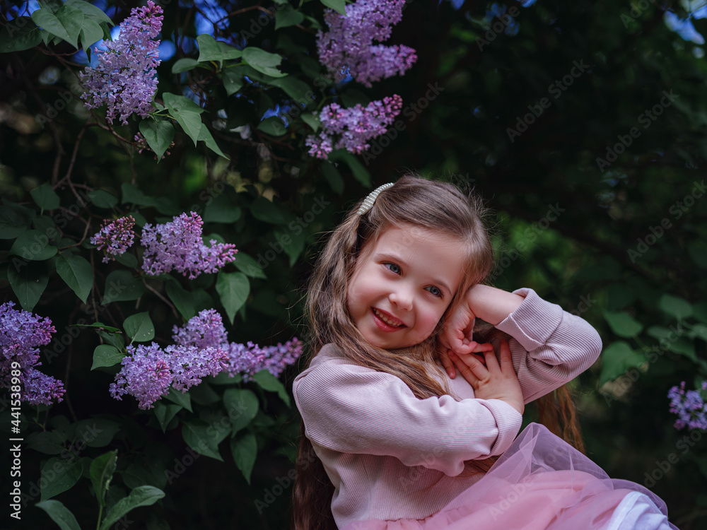 a little girl in a pink dress walking in a lilac garden a little girl in a pink dress walking in a lilac garden
