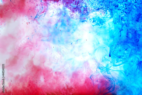 Beautiful ink mix macro. Blue, red, white colors watercolor are pouring. Paint movement macro. Fluid art painting. Moving flowing stream of liquid paint. Decorative abstract gradient background.