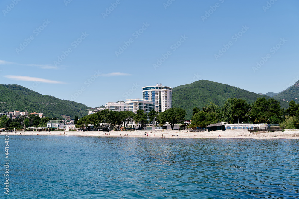 View from the sea to the beach and the hotel among the greenery in the mountains. Budva. Montenegro