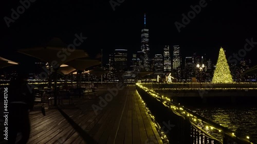 Illuminated Lower Manhattan View from J Owen Grundy Park in Jersey City at Winter Night. Christmas. Hudson River. New York City, USA. Jogger is Running