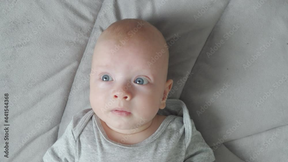 Face of baby boy with wide eyes lying on play mat top view, cute 3 month old newborn infant. High quality 4k footage Face of baby boy with wide eyes lying on play mat top view, cute 3 month old newborn infant. High quality 4k footage