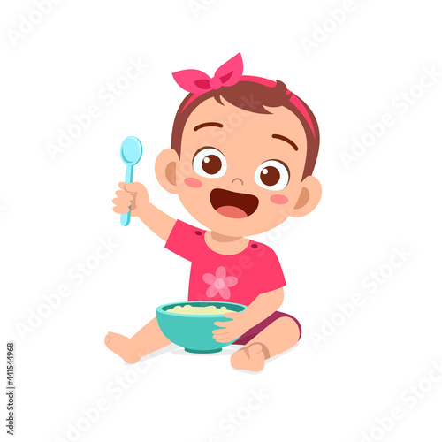 cute little baby girl eat porridge in bowl with spoon