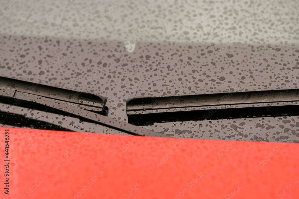 Automotive industry. Close up view of a pair of car wiper blades with small raindrops on window. Automotive industry. Close up view of a pair of car wiper blades with small raindrops on window.