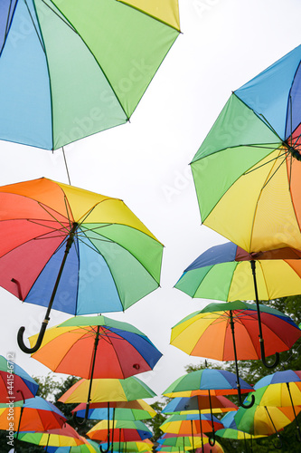 A lot of umbrellas hanged in a park. Beautiful view with a lot of color. Vivid photo.