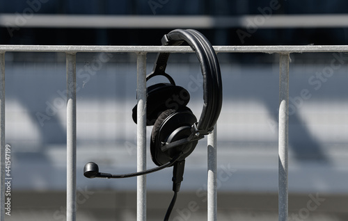 Sound industry. A pair of black headphones left on a steel fence.