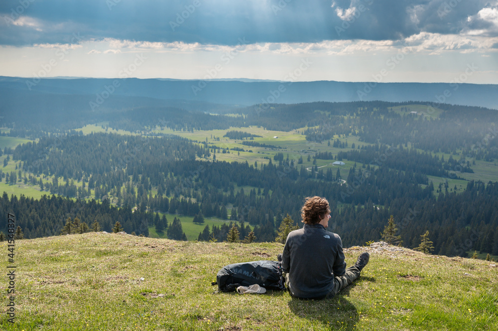 hiker enjoying the view over the hilly landscape of jura vaudoise near Col de Marchairuz hiker enjoying the view over the hilly landscape of jura vaudoise near Col de Marchairuz