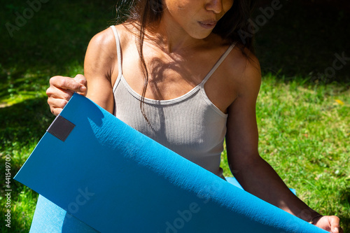 beautiful woman puts mat on the ground to do yoga in the park photo