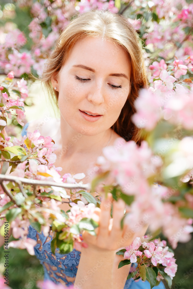 Close-up gentle portrait of a red-haired girl around her pink flowers from a cherry tree and an apple tree. Clean skin and youth concept. Close-up gentle portrait of a red-haired girl around her pink flowers from a cherry tree and an apple tree. Clean skin and youth concept.