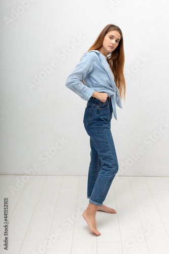 portrait of young attractive caucasian woman with long brown hair in shirt and blue jeans isolated on white background. skinny pretty female posing at studio. model tests of beautiful lady © Artem Zatsepilin