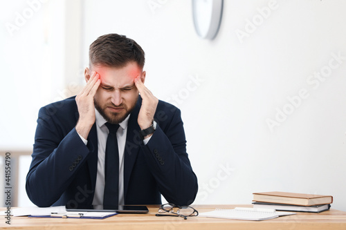 Man suffering from migraine at workplace in office photo