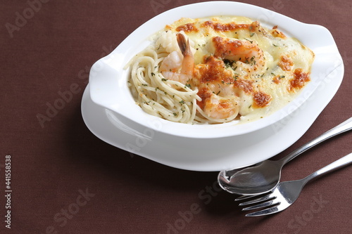 oven baked creamy cheese carbonara pasta with fresh big prawn in bowl western chef cuisine seafood menu in white and brown background
