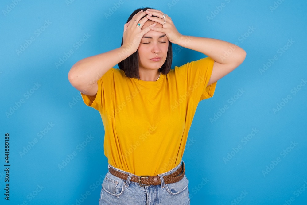 young beautiful brunette girl with short hair standing against blue background suffering from strong headache desperate and stressed because of overwork. Depression and pain concept. young beautiful brunette girl with short hair standing against blue background suffering from strong headache desperate and stressed because of overwork. Depression and pain concept.