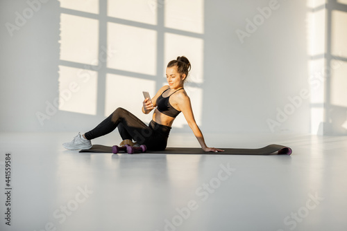 Happy athletic woman chatting on phone during fitness training. Healthy lifestyle  social activity on the Internet about sports