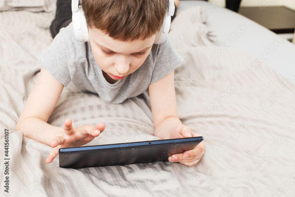 child boy lying on bed with pc tablet with wireless headphones child boy lying on bed with pc tablet with wireless headphones