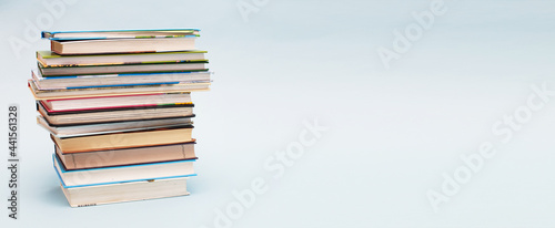 Stack of colorful books on blue background with copy space. Back to school concept. banner