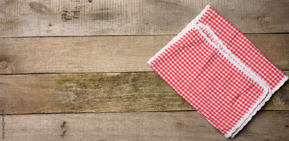 folded red and white cotton kitchen napkin on a wooden gray background folded red and white cotton kitchen napkin on a wooden gray background
