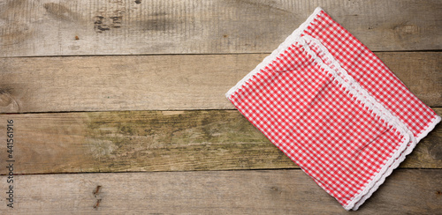 folded red and white cotton kitchen napkin on a wooden gray background