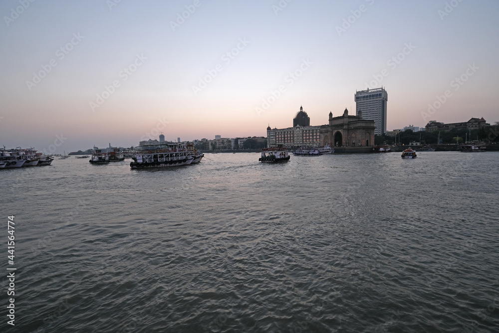Taj Mahal hotel, Gateway of India and tourist boats in water of Arabian Sea on sunset in Mumbai, India